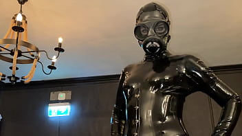 Transgender Dominatrix In Latex Catsuit, Gas Mask And Thigh High Boots.